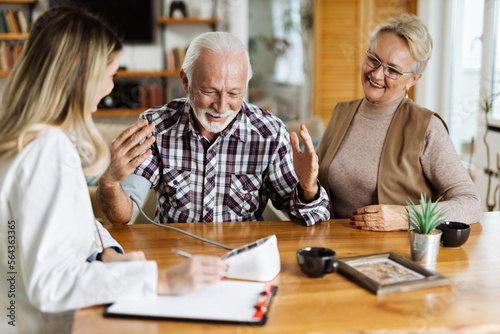 Female nurse checking blood pressure of a senior man during her home visit