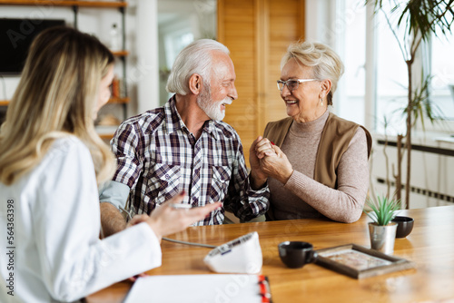 Female nurse checking blood pressure of a senior man during her home visit