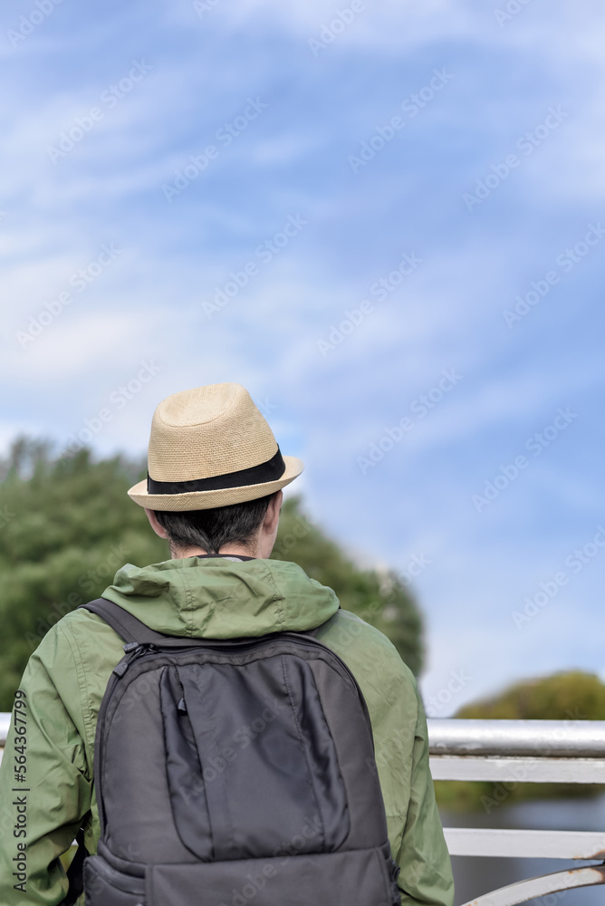 Traveler man with a backpack in nature against the blue sky. Tourist, backpacker in a hat looks at the sky. Traveler man with a backpack in nature against the blue sky. Tourist, backpacker in a hat looks at the sky.