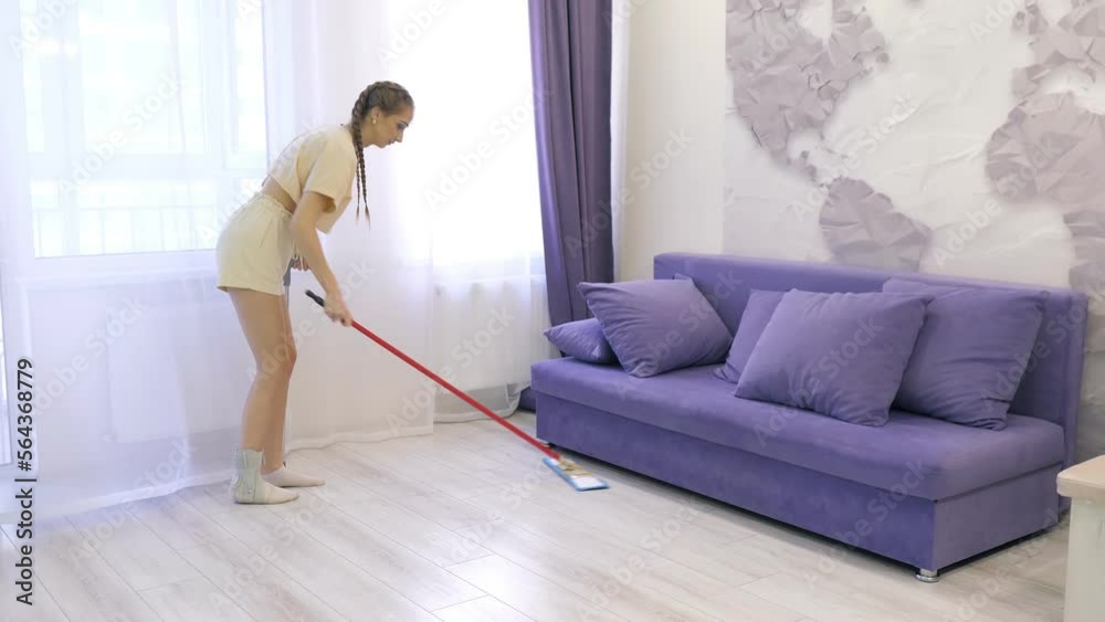 A young Caucasian girl moves around the house on one crutch and cleans