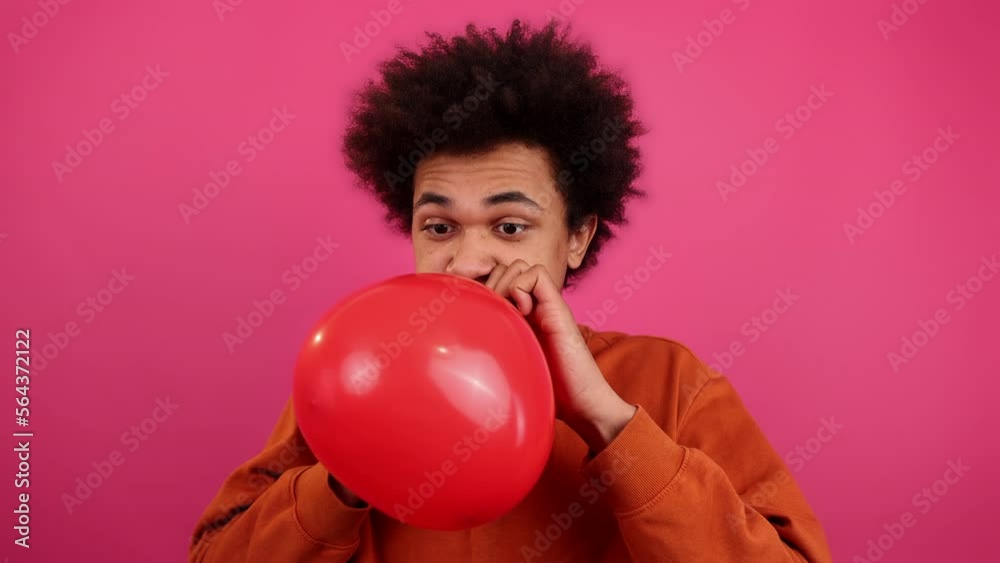 Close-up shot of happy, African American guy in late 20s holding a heart-shaped balloon. Smiling man presenting Valentine's symbol to his girlfriend. High quality 4k footage Close-up shot of happy, African American guy in late 20s holding a heart-shaped balloon. Smiling man presenting Valentine's symbol to his girlfriend. High quality 4k footage