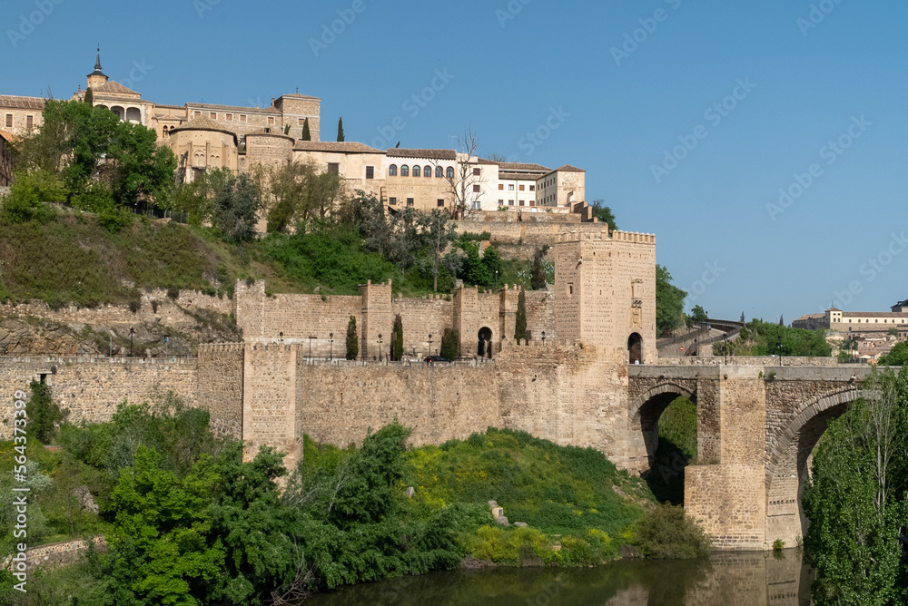 Toledo, España. April 29, 2022:Alcantara Roman Bridge with landscape and blue sky.