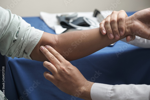 unrecognizable doctor's hands palpating with two fingers brachial pulse of female patient photo