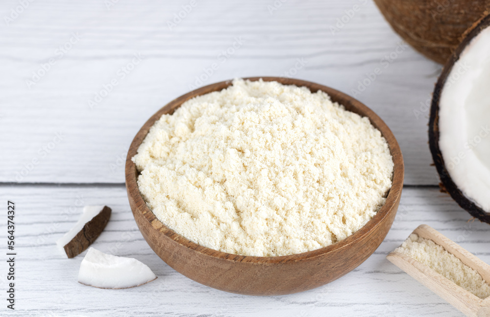 Coconut flour in a wooden bowl and fresh coconuts on a wooden background. Baking ingredients. Gluten free food. Coconut flour in a wooden bowl and fresh coconuts on a wooden background. Baking ingredients. Gluten free food.