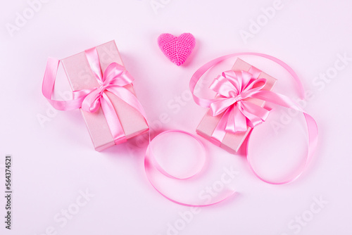 Happy Valentine's Day, Mother's Day and birthday greeting card. Knitted pink heart and gift boxes with a satin ribbon bow on a pink background
