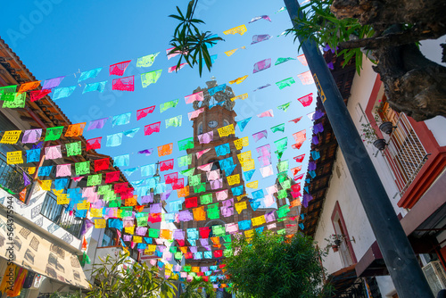 View from the street below of the The Church of Our Lady of Guadalupe with colorful flags strung across the street on a sunny morning in Puerto Vallarta, Mexico. photo