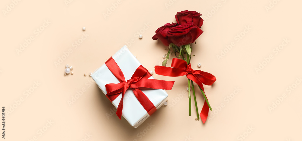 Gift box for Valentine's Day and roses on beige background, top view Gift box for Valentine's Day and roses on beige background, top view