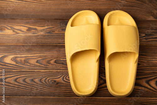 Rubber summer slippers. Replacement shoes for home or office. Yellow slippers on a background of brown space. Relax concepts. Space for text.Space for copy.