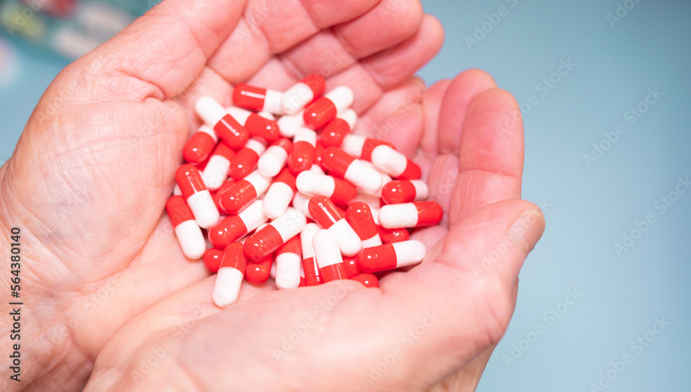 Many coloured pills in a Senior's hands on blue background. Painful old age. Caring for the health of the elderly. Many coloured pills in a Senior's hands on blue background. Painful old age. Caring for the health of the elderly.