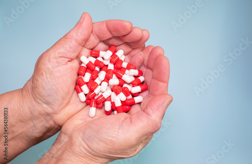 Many coloured pills in a Senior's hands on blue background. Painful old age. Caring for the health of the elderly. 