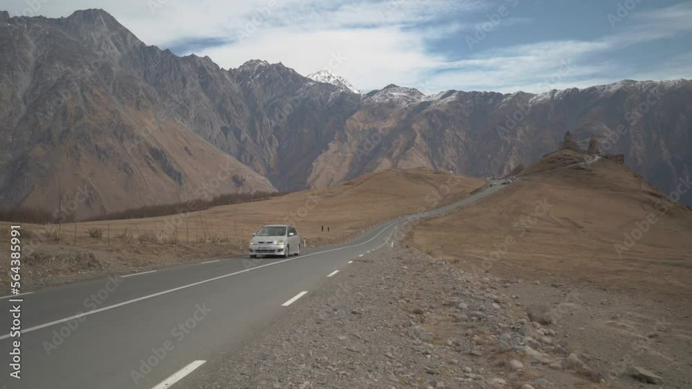 A car drives from ancient church in mountains A car drives from ancient church in mountains