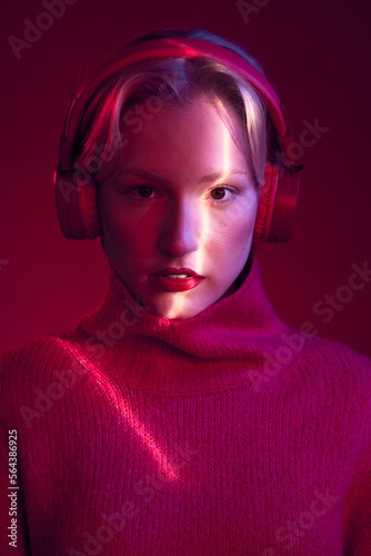 Tableau sur toile Portrait of a smiling girl enjoying music isolated on magenta background