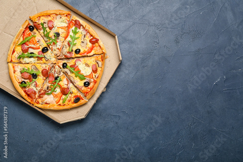 Cardboard box with delicious pizza on dark background