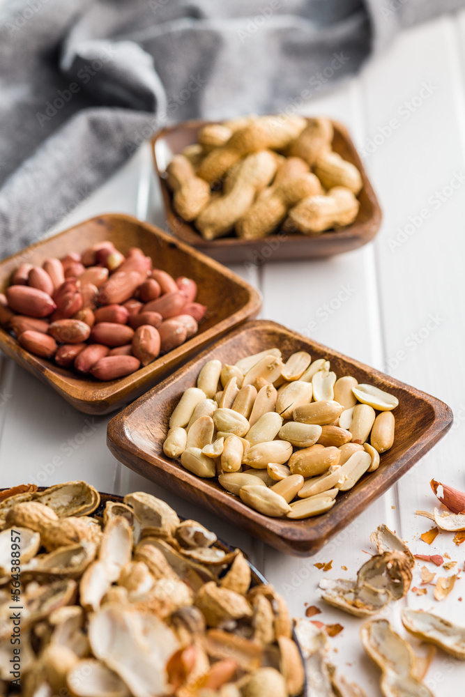 Unpeeled and peeled peanuts in bowl on kitchen table.