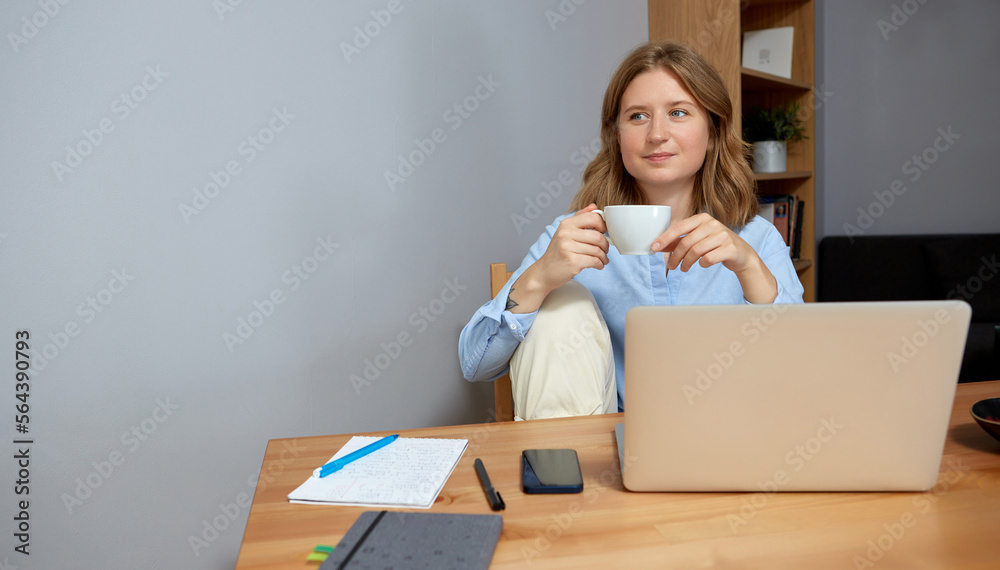 Beautiful young woman working on laptop while sitting at the living room, drinking coffee. Beautiful young woman working on laptop while sitting at the living room, drinking coffee.