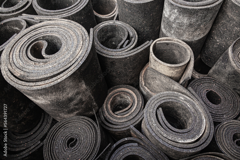 Old sheet rubber of black color, twisted into rolls, top view. rubber waste. Old sheet rubber of black color, twisted into rolls, top view. rubber waste.