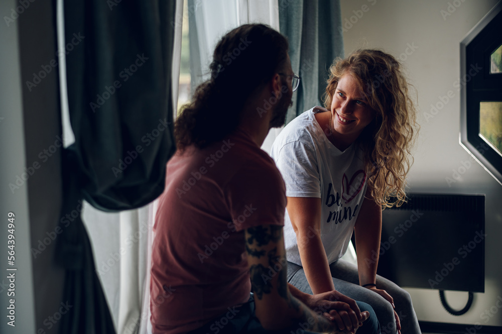 Obraz premium Couple sitting near the window in the bedroom at home