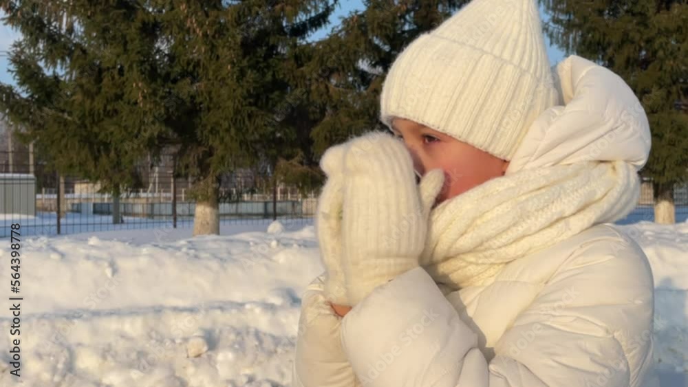 a little girl in figure skates drinks hot tea on a skating rink in winter, a girl warms herself with a hot drink in winter a little girl in figure skates drinks hot tea on a skating rink in winter, a girl warms herself with a hot drink in winter