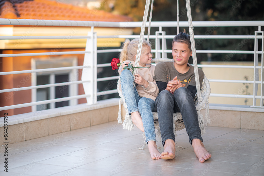 First love, young teens couple boy and girl swinging on swing together,  first dating, flower and kids love. Stock Photo | Adobe Stock