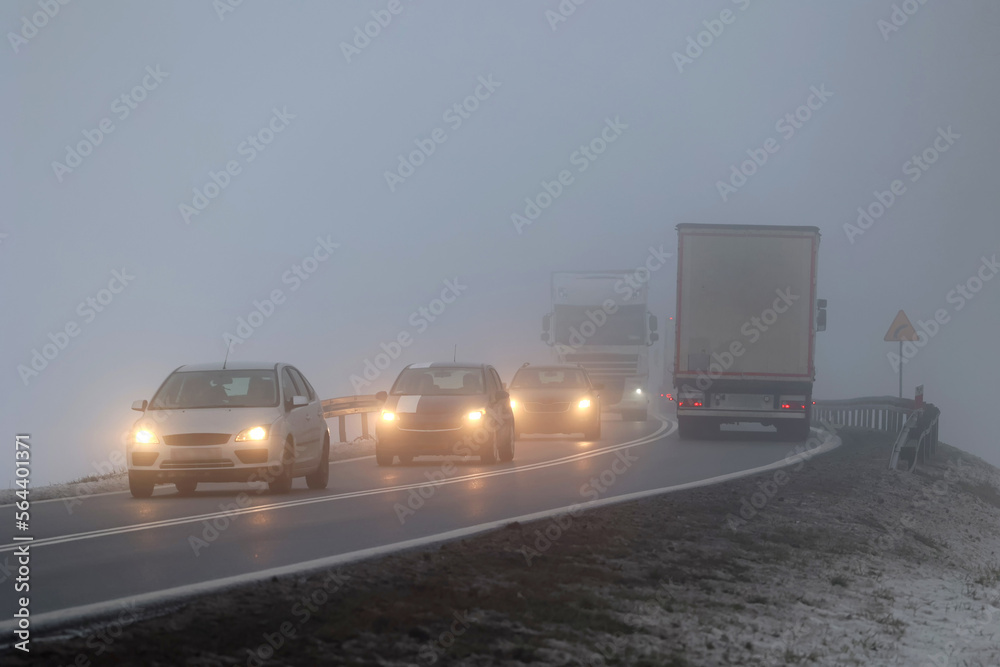 Ruch pojazdów w gęstej mgle na drodze wieczorem. Niebezpiecznie. - obrazy, fototapety, plakaty 