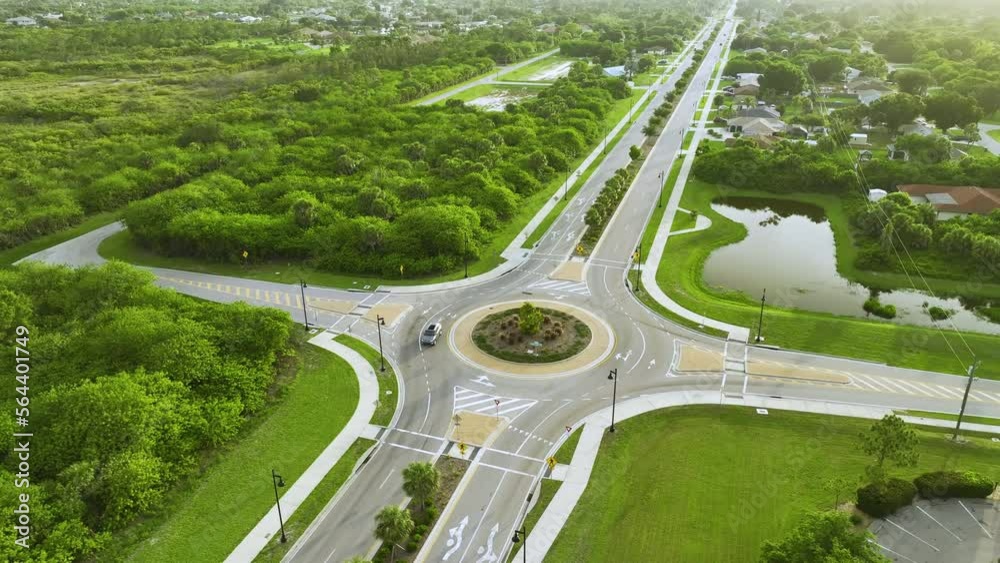 Aerial view of american suburban area with rural road roundabout intersection with moving cars traffic. Circular transportation crossroads in Florida