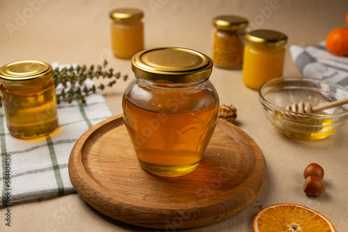 A glass jar with honey and a wooden stick in the background. Craft honey products. 