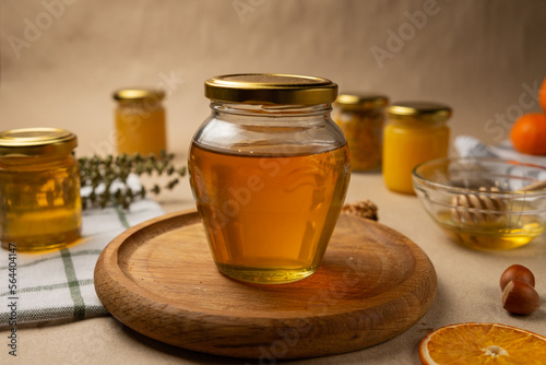 A glass jar with honey and a wooden stick in the background. Craft honey products. 