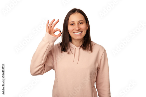 Content young smiling woman is showing okay gesture in a white studio.