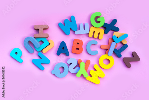 Colorful wooden alphabets on pink background.