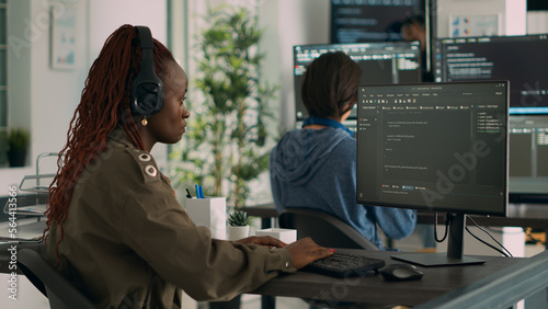 African american software engineer working focused on programming it language at computer, typing html script. Database programer writing code with algorithms on terminal window.