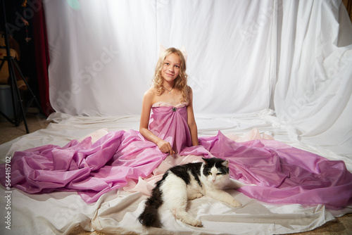 Portrait of cute kid girl posing in pink beautiful dress on a white background. Model in studio looking as gentle magic princess from fairy taly having photo shoot on white background photo