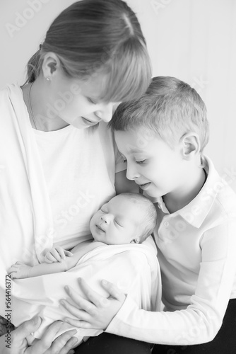 newborn baby in the arms of mother and older child, black and white photo, monochrome. parental care for a new life