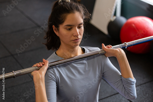 Close up of beautiful sportswoman doing exercises indoors in gym, lifting barbell 