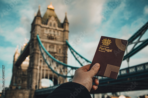 London, UK - 2023: Hand holding a portuguese passport in front of the Tower Bridge. photo