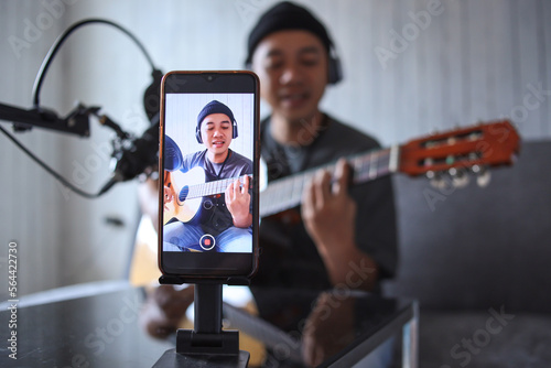 Photography Asian influencer playing guitar during podcast or live video broadcast for the a