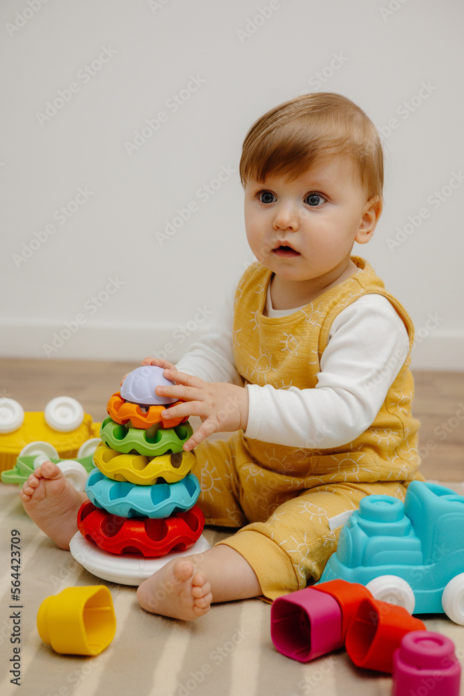 A cute child is playing with a colorful rainbow toy pyramid. Toys for small children. A cute child is playing with a colorful rainbow toy pyramid. Toys for small children.