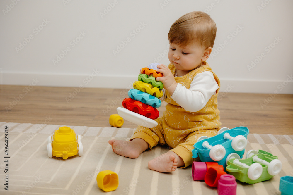A cute child is playing with a colorful rainbow toy pyramid. Toys for small children. A cute child is playing with a colorful rainbow toy pyramid. Toys for small children.
