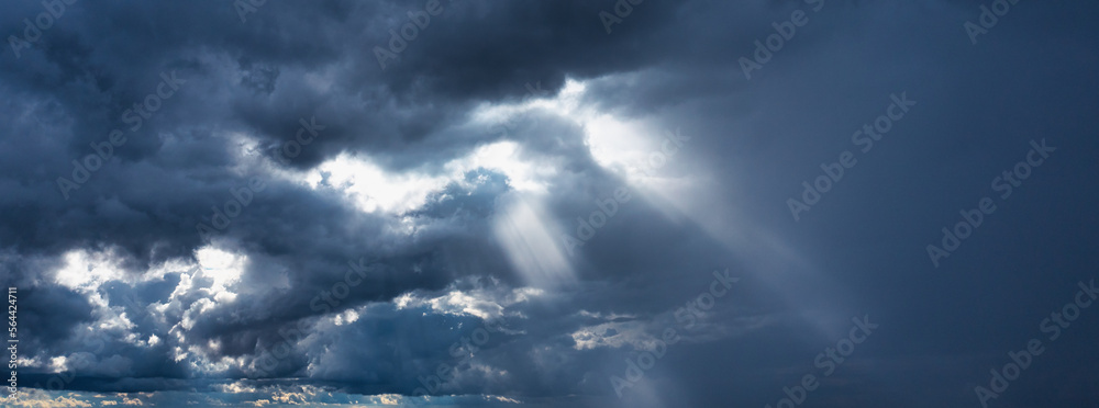 Obraz premium Storm clouds and rays of the sun on a dark background.