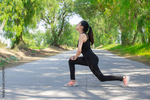 mujer delgada y joven caucasica estirandose y haciendo ejercicio estilo de vida fitness en un entorno de naturaleza en la carretera  photo