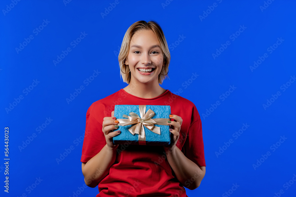 Birthday woman blonde hair with gift box on blue background. Girl smiling. Birthday woman blonde hair with gift box on blue background. Girl smiling.