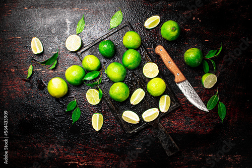 Sliced lime with leaves on a cutting board with a knife.