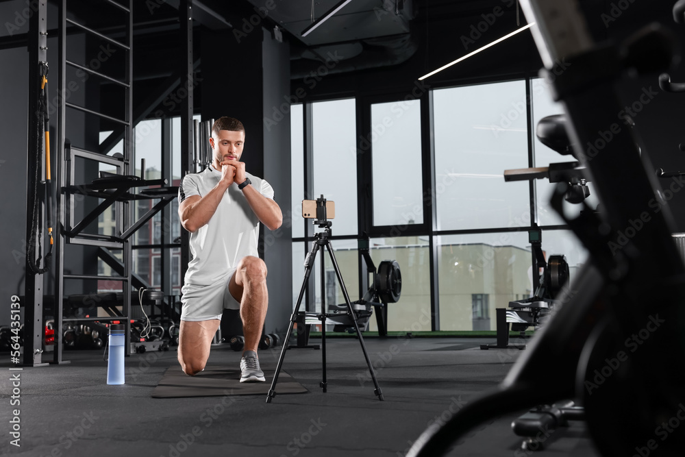 Trainer streaming online workout with phone at gym Trainer streaming online workout with phone at gym