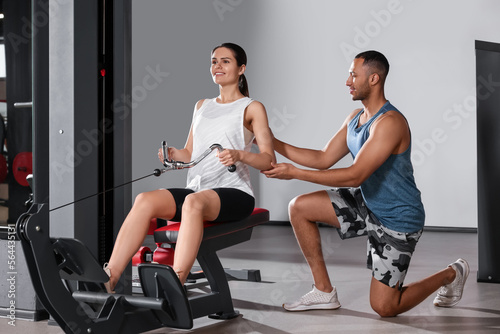 Trainer explaining woman how to do exercise properly in modern gym