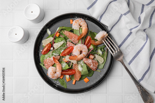 Delicious salad with pomelo, shrimps and tomatoes on white tiled table, flat lay