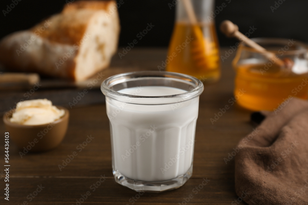 Glass with milk near butter, honey and bread on wooden table Glass with milk near butter, honey and bread on wooden table