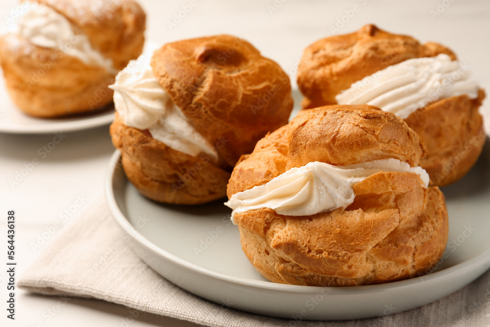 Delicious profiteroles with cream filling on table, closeup Delicious profiteroles with cream filling on table, closeup