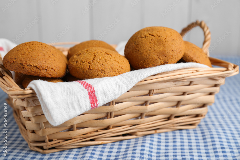 Wicker basket with tasty oatmeal cookies on checkered cloth Wicker basket with tasty oatmeal cookies on checkered cloth