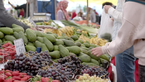 A woman feels the avocado and chooses a ripe one. Open air market. People in bazaar choose products