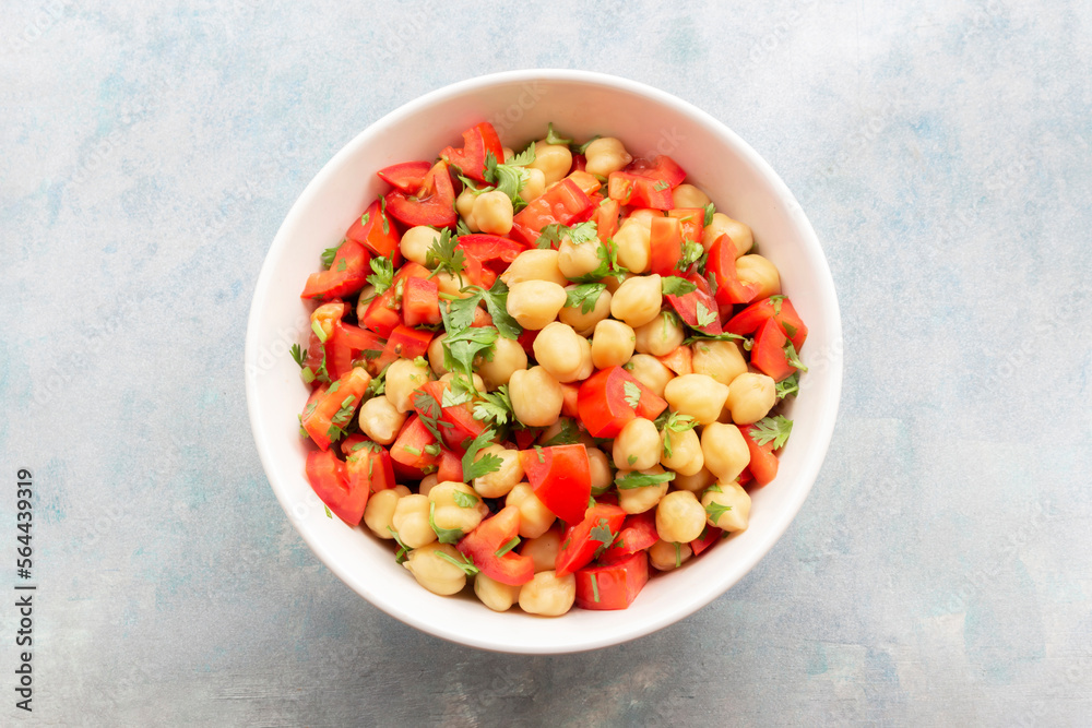 Healthy food chickpeas salad add tomato coriander in white bowl on blue wood background.