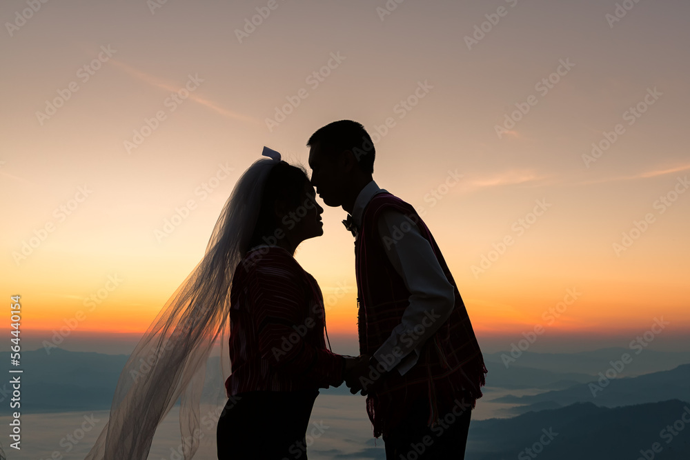 silhouette of wedding Couple in love kissing and holding hand together during sunrise with morning sky background